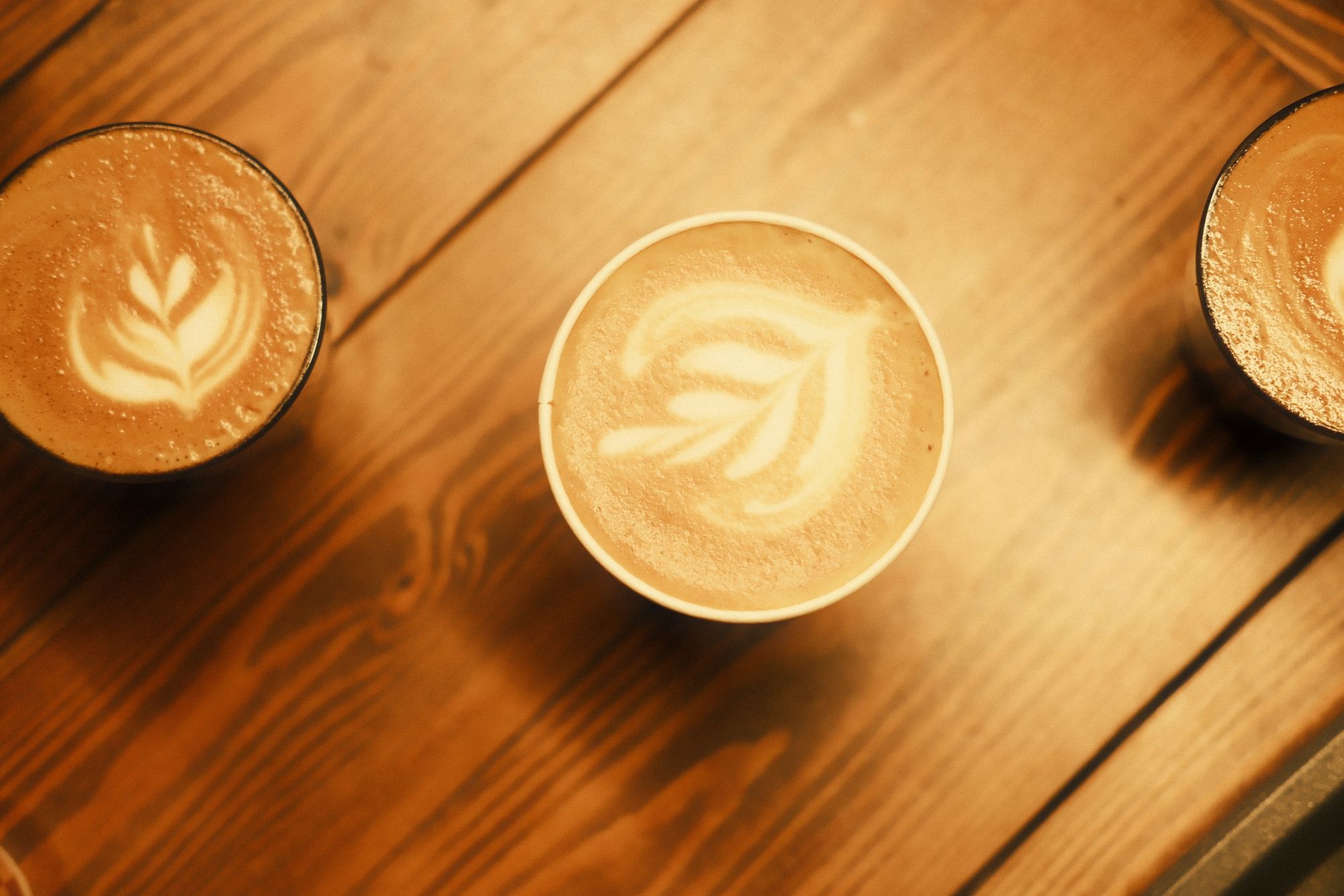 Ahşap masada latte art yapılmış kahve fincanı