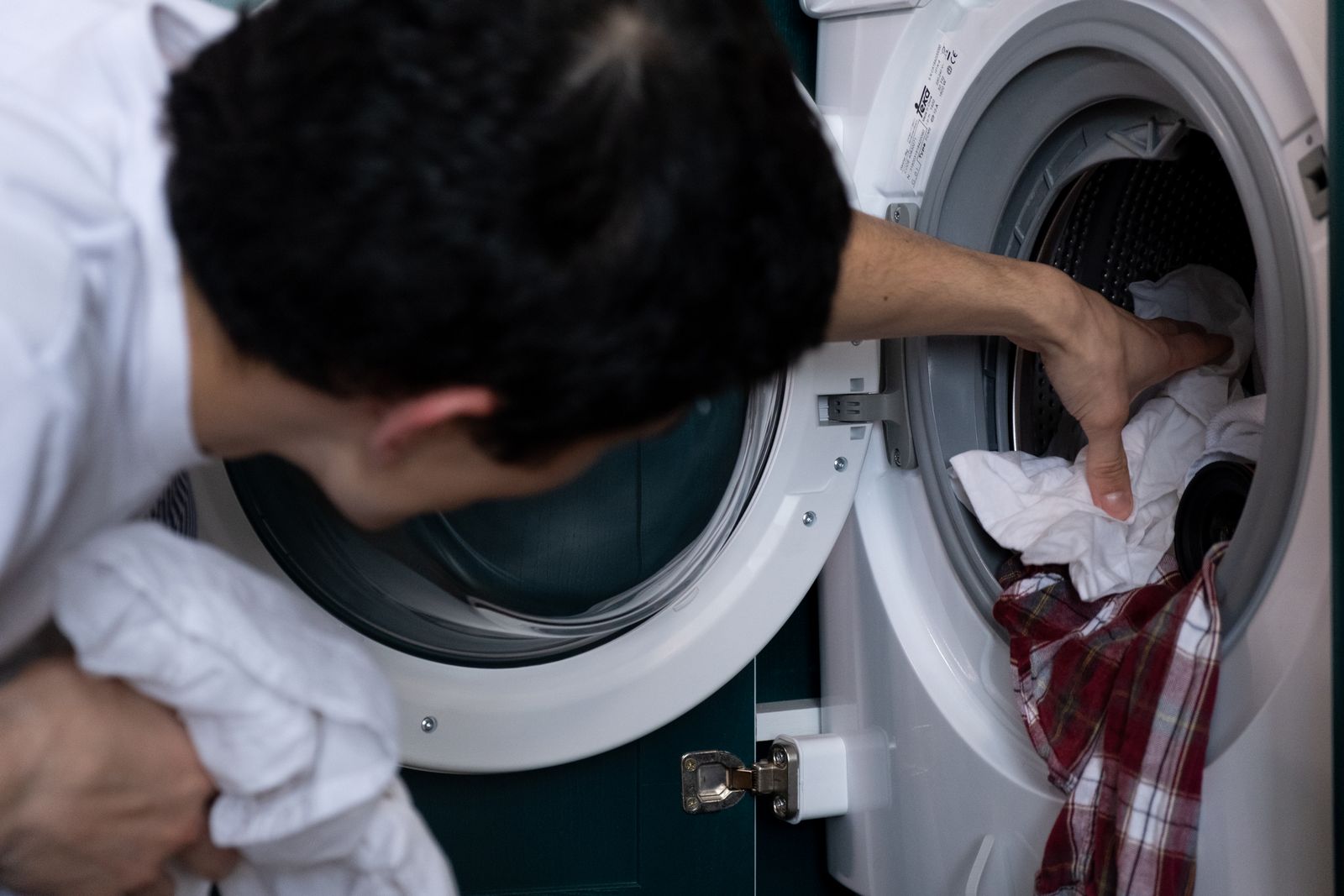 Çamaşır makinesinin içini inceleyen bir teknisyen