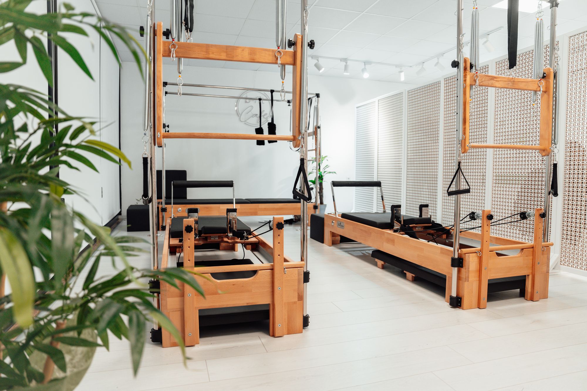 Bitkilerle beyaz bir odada ahşap pilates kuleleri